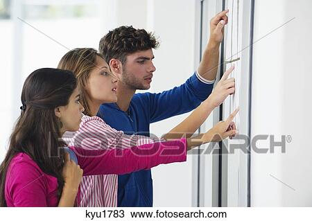 Stock Image - University students checking bulletin board for test result. Fotosearch