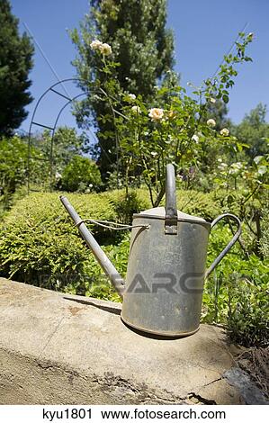 Watering can on a rock in a garden View Large Photo Image Stock Image - Watering can on a rock in a garden. Fotosearch