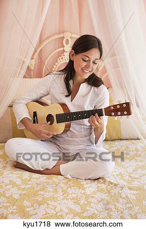 Woman playing guitar on the bed View Large Photo Image Stock Photo - Woman playing guitar on the bed. Fotosearch