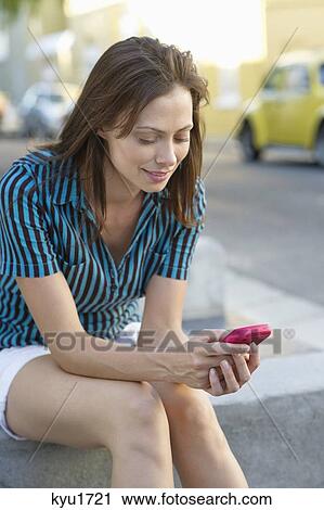 Young woman text messaging with a mobile phone View Large Photo Image Stock Image - Young woman text messaging with a mobile phone. Fotosearch