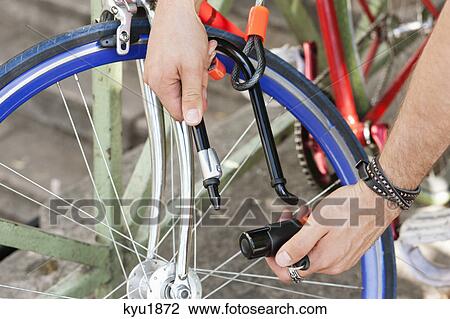 Stock Image - Close-up of a man's hands locking his bicycle, Paris, Ile-de-France, France. Fotosearch