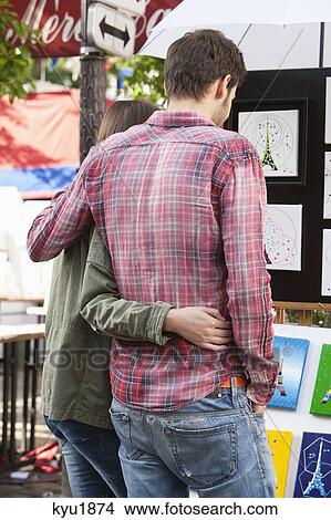 Picture - Couple looking at postcards of Eiffel Tower at a market stall, Paris, Ile-de-France, France. Fotosearch