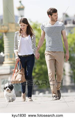 Stock Image - Couple walking with a puppy, Paris, Ile-de-France, France. Fotosearch
