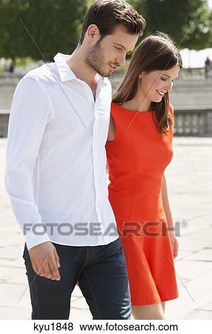 Stock Photo - Couple walking with arms around and smiling, Paris, Ile-de-France, France. Fotosearch