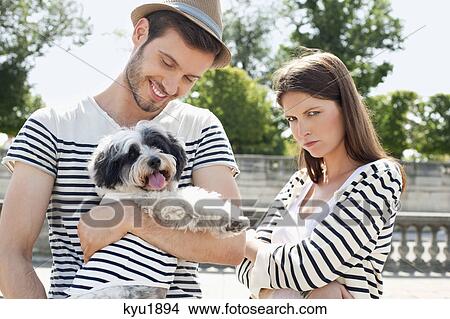 Picture - Man carrying a puppy and smiling with a woman looking sad, Paris, Ile-de-France, France. Fotosearch