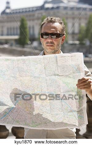 Stock Image - Man reading a map, Terrasse De l'Orangerie, Jardin des Tuileries, Paris, Ile-de-France, France. Fotosearch