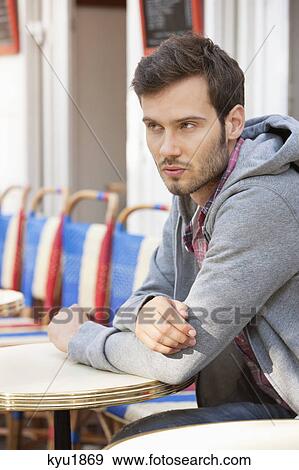 Stock Photo - Man sitting at a sidewalk cafe, Paris, Ile-de-France, France. Fotosearch