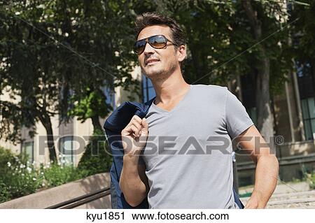 Stock Image - Man standing in a garden, Paris, Ile-de-France, France. Fotosearch