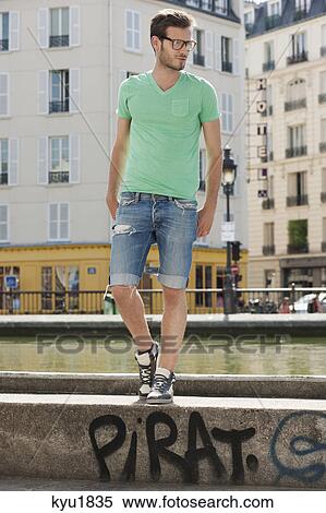 Stock Photography - Man standing on the ledge of a canal, Canal St Martin, Paris, Ile-de-France, France. Fotosearch