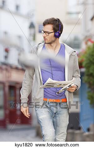 Stock Image - Man walking on the street with a newspaper, Paris, Ile-de-France, France. Fotosearch