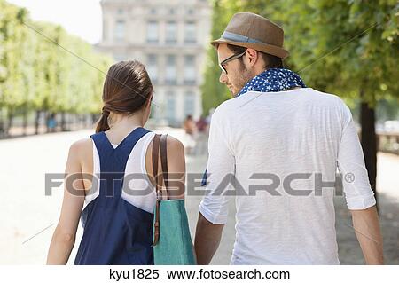 Stock Photography - Rear view of a couple walking together, Paris, Ile-de-France, France. Fotosearch