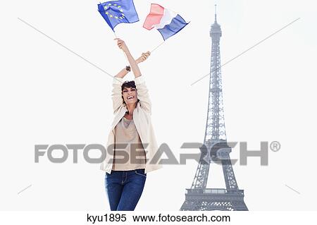 Stock Photography - Woman holding a European Union flag and a French flag with the Eiffel Tower in the background, Paris, Ile-de-France, France. Fotosearch