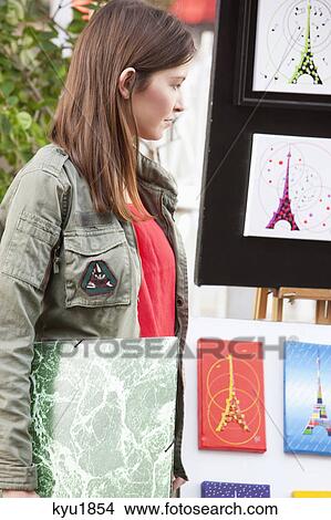 Picture - Woman looking at postcards of Eiffel Tower at a market stall, Paris, Ile-de-France, France. Fotosearch