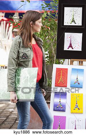 Stock Photograph - Woman looking at postcards of Eiffel Tower at a market stall, Paris, Ile-de-France, France. Fotosearch