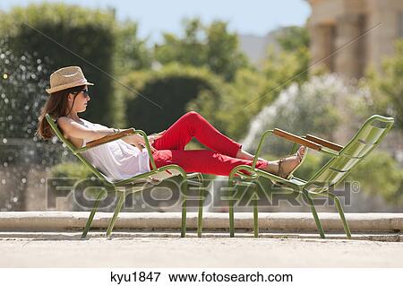 Stock Photo - Woman resting in a chair near a pond, Bassin octogonal, Jardin des Tuileries, Paris, Ile-de-France, France. Fotosearch