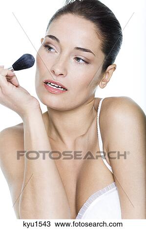 Stock Image - Young woman applying blush. Fotosearch
