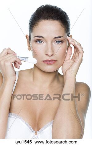 Stock Photography - Young woman applying blush. Fotosearch