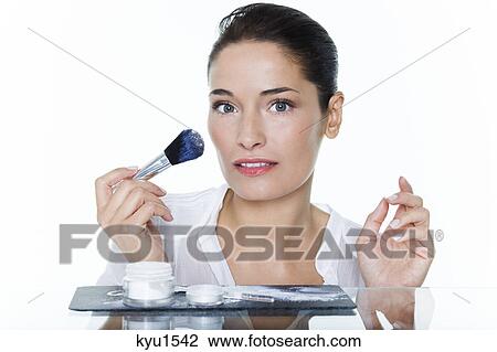 Stock Image - Young woman holding make-up brush. Fotosearch