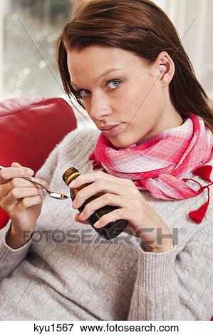Stock Photo - Young woman taking cough medicine. Fotosearch