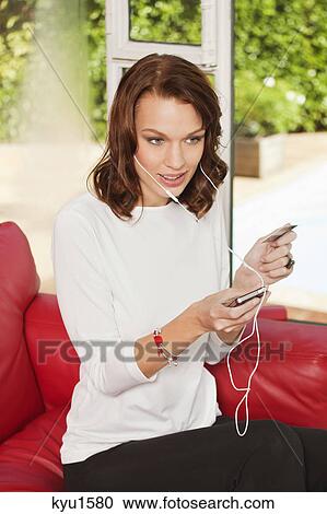 Stock Image - Young woman using iPhone, holding credit card. Fotosearch