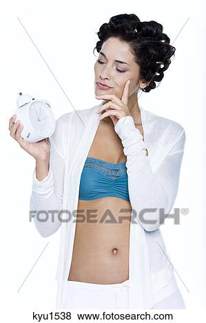 Young woman with hair clips, holding alarm clock View Large Photo Image Stock Photo - Young woman with hair clips, holding alarm clock. Fotosearch