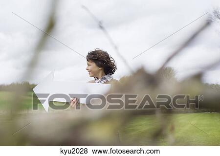 Boy holding an arrow sign in a field View Large Photo Image Stock Photo - Boy holding an arrow sign in a field. Fotosearch