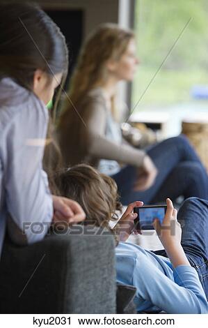 Boy using phone with his sister and mother at home View Large Photo Image Stock Image - Boy using phone with his sister and mother at home. Fotosearch
