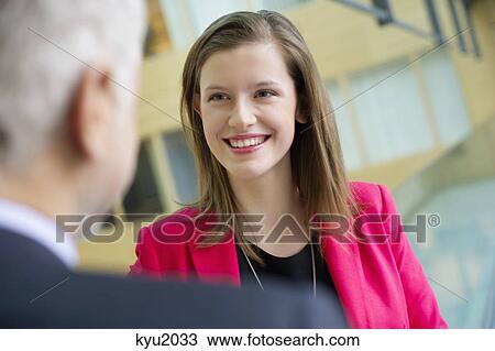Stock Image - Business executives discussing in an office corridor. Fotosearch