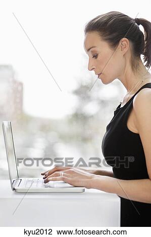 Stock Image - Businesswoman working on a laptop in an office. Fotosearch
