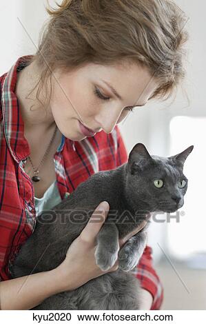 Stock Image - Close-up of a woman holding a black cat. Fotosearch