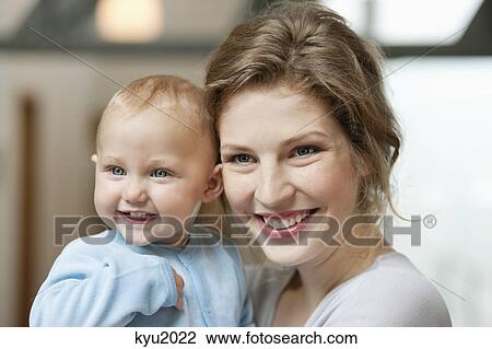 Close-up of a woman smiling with her baby girl View Large Photo Image Stock Image - Close-up of a woman smiling with her baby girl. Fotosearch