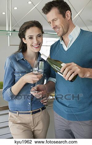 Stock Image - Couple drinking wine in the kitchen. Fotosearch
