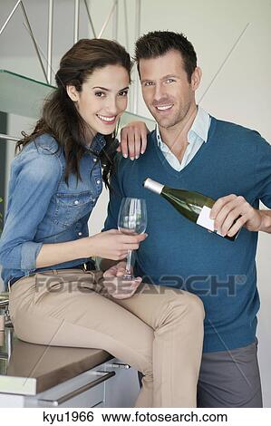 Stock Photograph - Couple drinking wine in the kitchen. Fotosearch