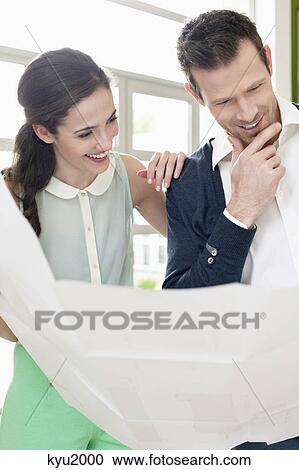 Stock Image - Couple reading a blueprint. Fotosearch