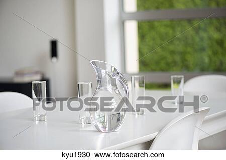 Stock Image - Glasses and pitcher on a table. Fotosearch