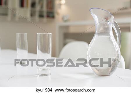 Jug of water and glasses on a dining table View Large Photo Image Picture - Jug of water and glasses on a dining table. Fotosearch