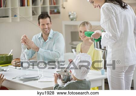 Stock Photo - Little boy assisting his mother in serving dinner. Fotosearch