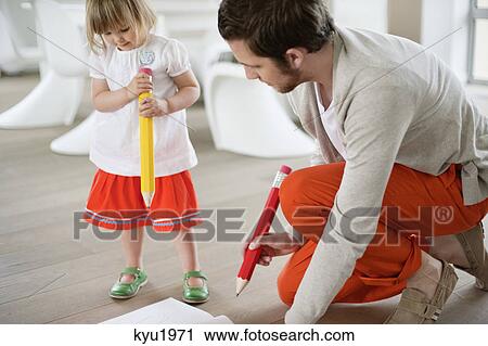 Stock Image - Man and his daughter drawing with large pencils. Fotosearch