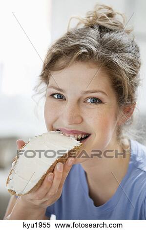 Portrait of a woman eating toast with cream spread on it View Large Photo Image Stock Photography - Portrait of a woman eating toast with cream spread on it. Fotosearch