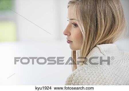Picture - Serious woman sitting in a room. Fotosearch