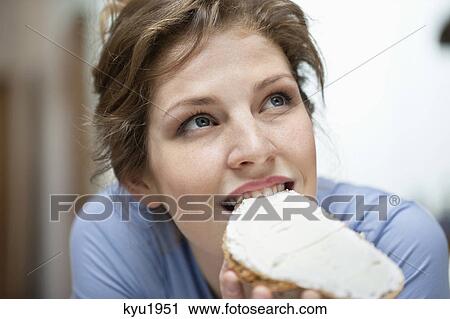 Woman eating a toast with cream spread on it View Large Photo Image Stock Image - Woman eating a toast with cream spread on it. Fotosearch