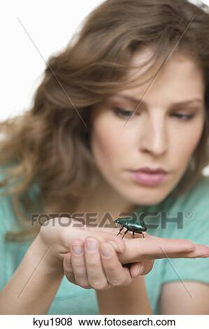 Stock Photo - Woman looking at a beetle on her hand. Fotosearch