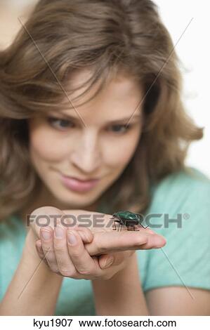 Stock Photo - Woman looking at a beetle on her hands. Fotosearch