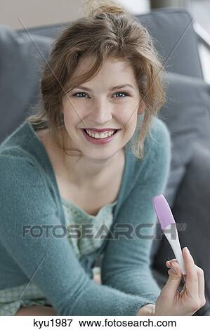 Stock Photo - Woman looking happy after checking her pregnancy test. Fotosearch