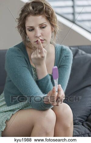 Stock Photo - Woman looking sad after checking her pregnancy test. Fotosearch