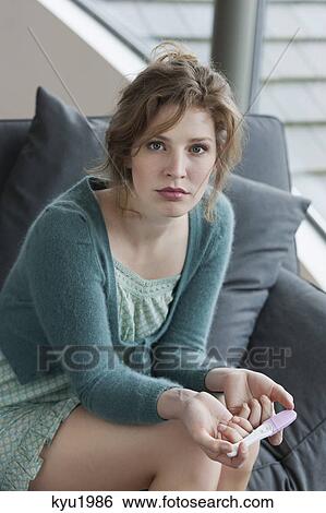 Stock Photograph - Woman looking sad after checking her pregnancy test. Fotosearch