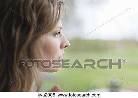 Stock Photograph - Woman looking through the glass of window. Fotosearch