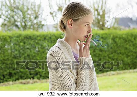 Woman smoking cigarette in park View Large Photo Image Stock Image - Woman smoking cigarette in park. Fotosearch