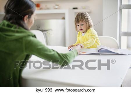Stock Image - Woman teaching her daughter at home. Fotosearch