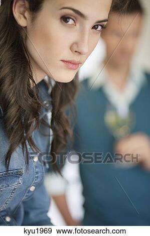 Stock Photo - Woman thinking with her husband in the background. Fotosearch